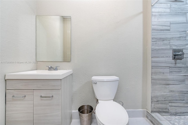 bathroom with vanity, tiled shower, and toilet