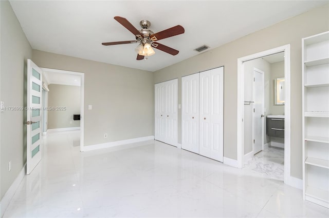 unfurnished bedroom with connected bathroom, two closets, and ceiling fan