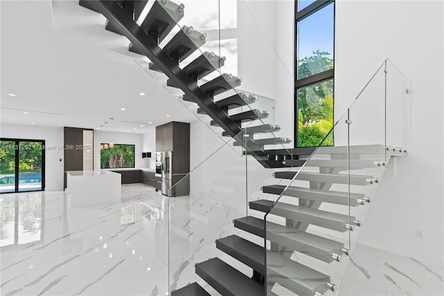 stairway featuring a high ceiling and a wealth of natural light