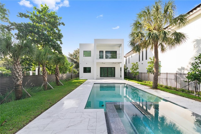 rear view of property featuring a swimming pool with hot tub, a patio, and a balcony