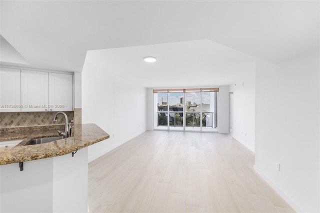 unfurnished living room featuring sink and light hardwood / wood-style flooring