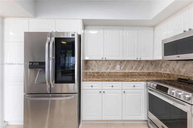 kitchen with white cabinetry, stainless steel appliances, and dark stone counters