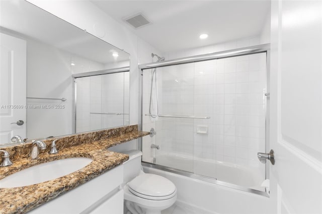 full bathroom featuring vanity, combined bath / shower with glass door, and toilet