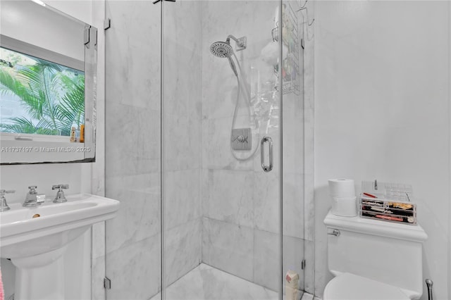 bathroom featuring a shower with shower door, sink, and toilet