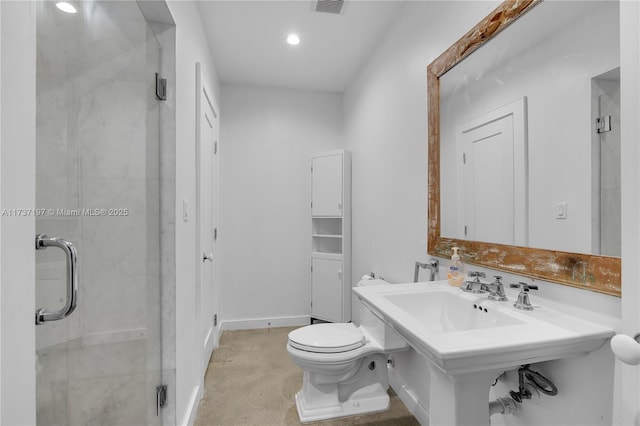 bathroom featuring a shower with shower door, sink, and toilet