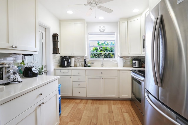 kitchen featuring sink, appliances with stainless steel finishes, white cabinets, light hardwood / wood-style floors, and backsplash