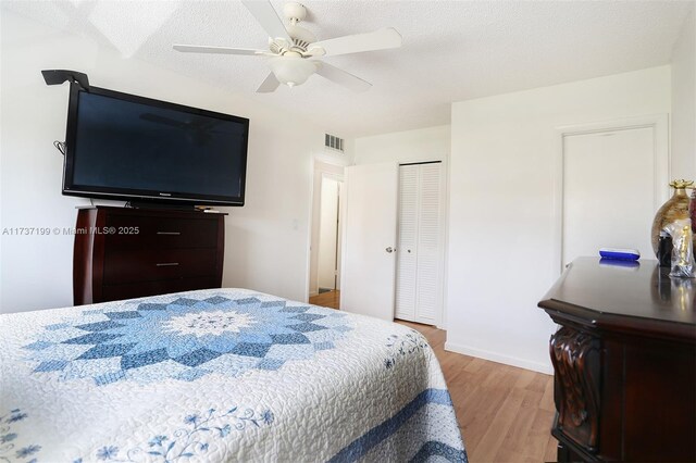 bedroom with ceiling fan, light hardwood / wood-style flooring, a closet, and a textured ceiling