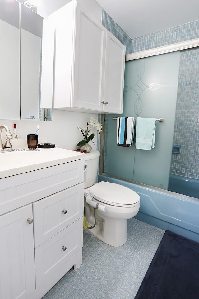 full bathroom with tile patterned flooring, bath / shower combo with glass door, vanity, and toilet