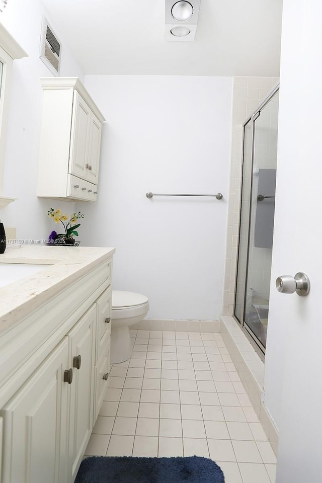 bathroom with toilet, vanity, tile patterned floors, and a shower with shower door