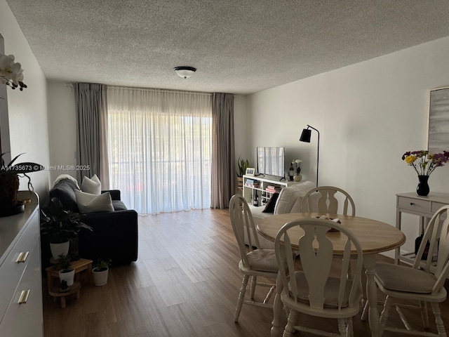 dining room with a textured ceiling and light hardwood / wood-style flooring