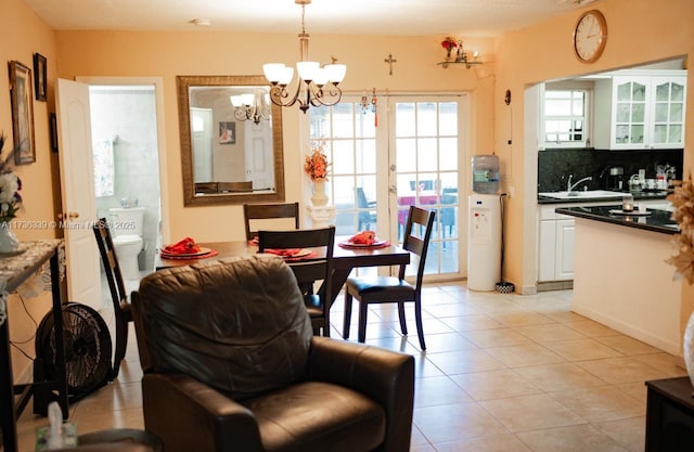 dining space with sink, light tile patterned floors, an inviting chandelier, and french doors