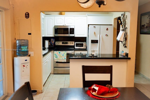 kitchen with stainless steel appliances, kitchen peninsula, light tile patterned floors, and white cabinets