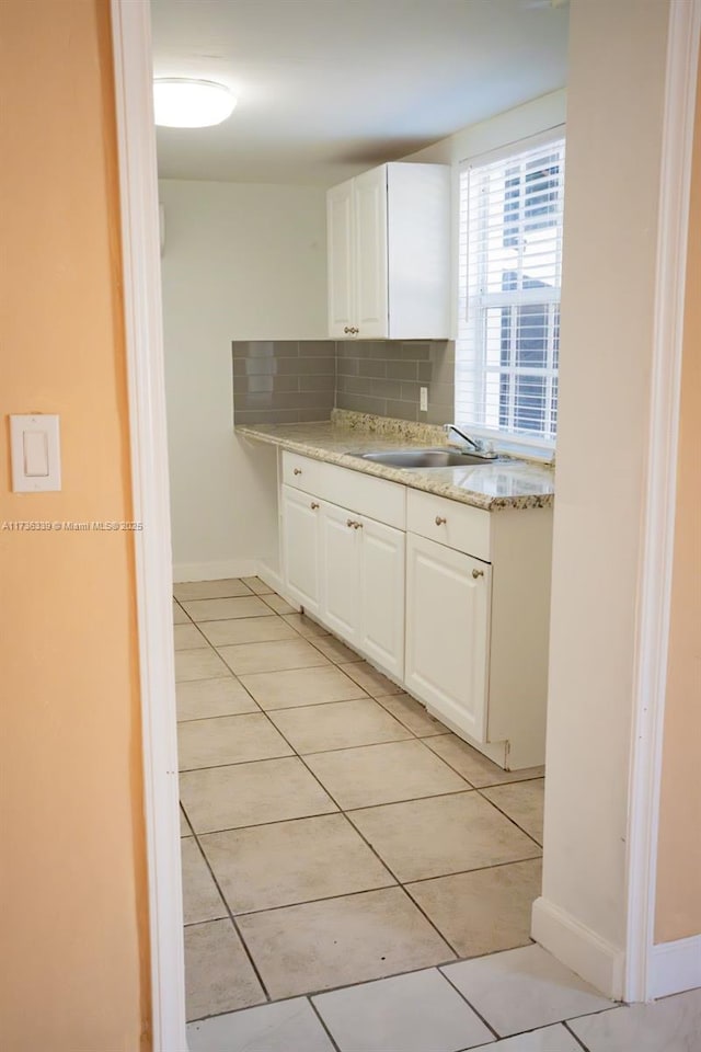 kitchen featuring white cabinetry, sink, light tile patterned floors, and decorative backsplash