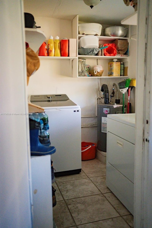 laundry area featuring electric water heater, light tile patterned floors, and independent washer and dryer