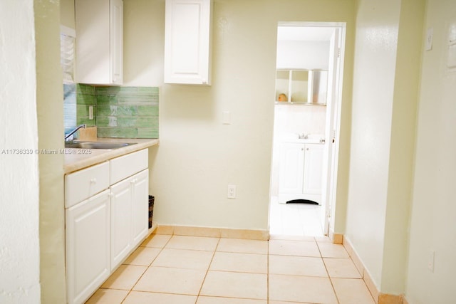 kitchen with sink, light tile patterned floors, and white cabinets