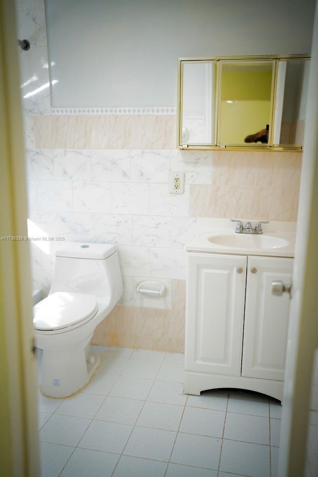 bathroom featuring vanity, tile patterned flooring, tile walls, and toilet