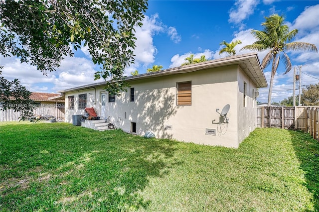 rear view of property featuring central AC and a lawn