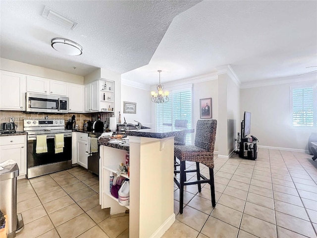 kitchen with light tile patterned flooring, appliances with stainless steel finishes, white cabinets, a kitchen breakfast bar, and kitchen peninsula