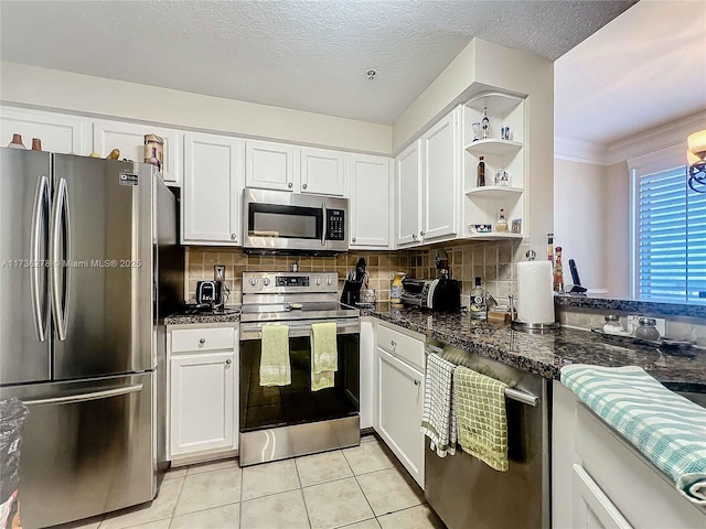 kitchen with white cabinetry, stainless steel appliances, decorative backsplash, and light tile patterned floors