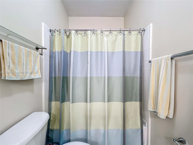 bathroom with a textured ceiling, toilet, and shower / bath combo