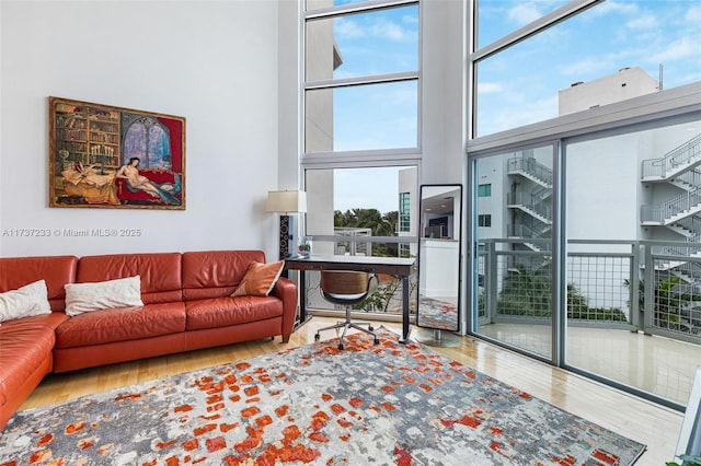 living room with hardwood / wood-style flooring, a towering ceiling, and a wall of windows