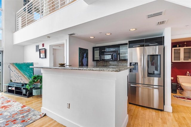 kitchen featuring tasteful backsplash, stainless steel fridge with ice dispenser, light hardwood / wood-style flooring, and stone counters