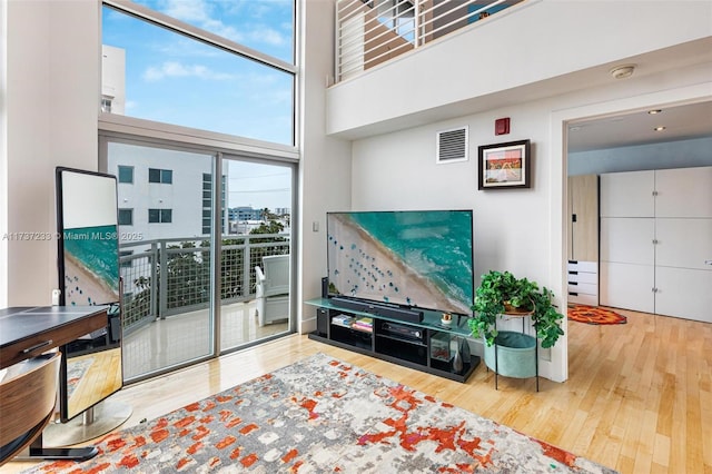 living room with hardwood / wood-style flooring, a wall of windows, and a high ceiling