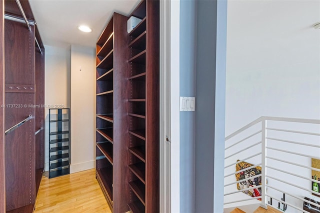 walk in closet with light hardwood / wood-style flooring