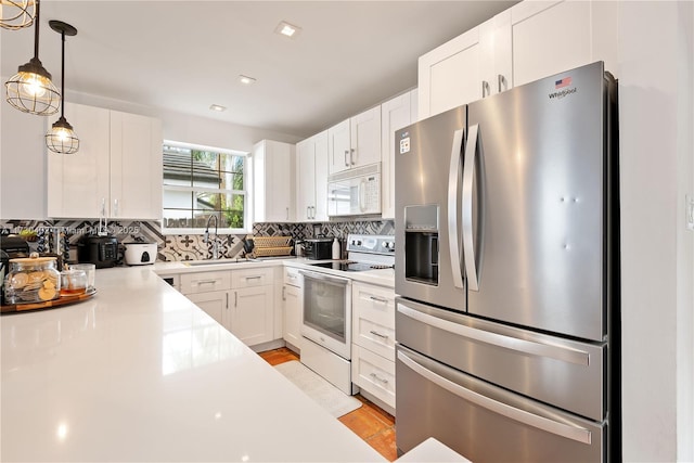 kitchen with hanging light fixtures, white cabinetry, white appliances, and decorative backsplash