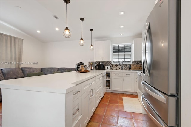 kitchen featuring stainless steel fridge, white cabinetry, backsplash, decorative light fixtures, and kitchen peninsula