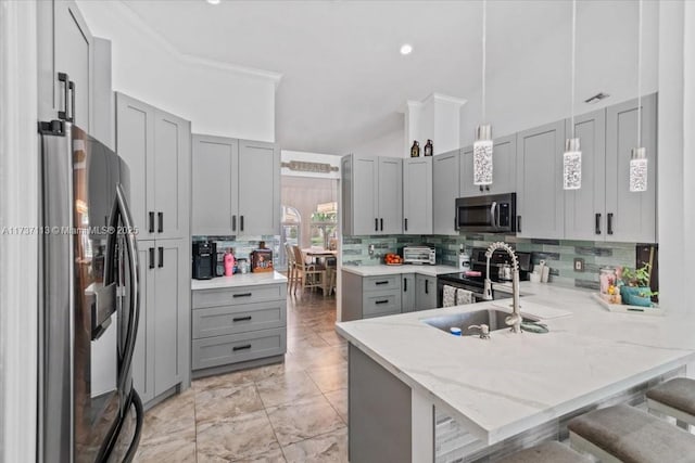 kitchen with a breakfast bar, hanging light fixtures, appliances with stainless steel finishes, gray cabinets, and kitchen peninsula