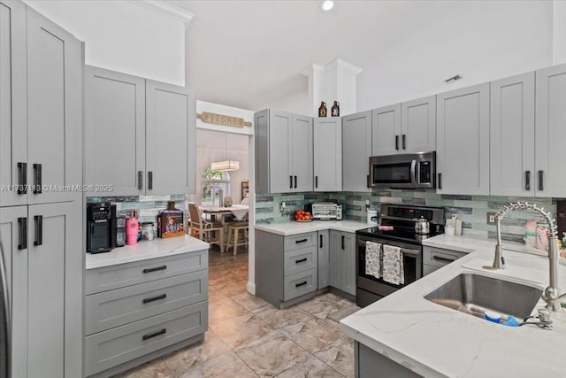 kitchen with sink, appliances with stainless steel finishes, gray cabinetry, tasteful backsplash, and vaulted ceiling