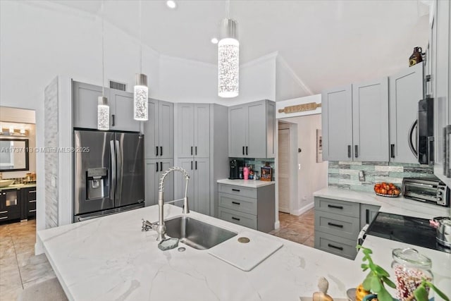 kitchen with appliances with stainless steel finishes, decorative light fixtures, gray cabinets, and sink