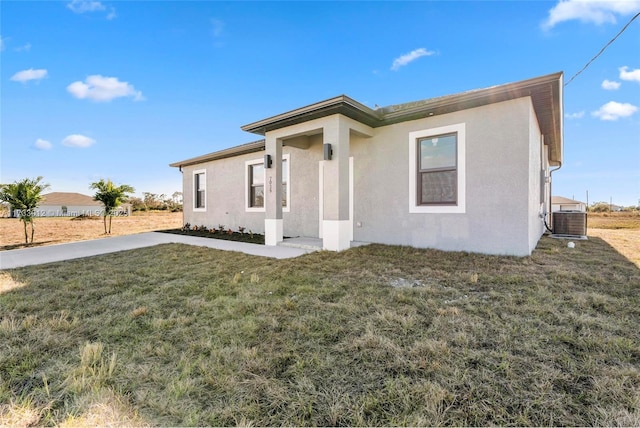 view of front facade with a front lawn, cooling unit, and stucco siding