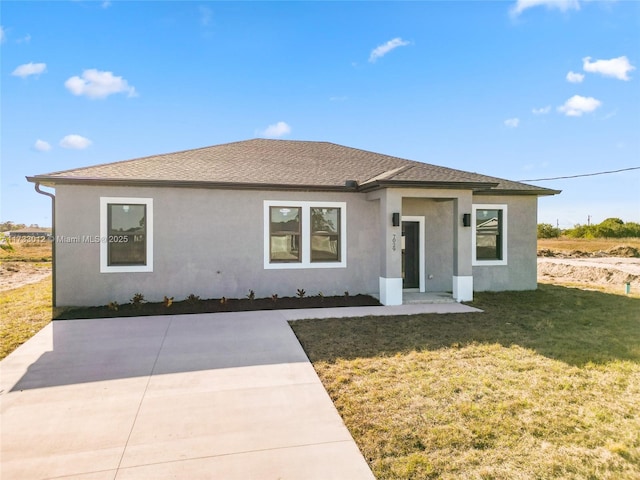 view of front of property featuring stucco siding, a shingled roof, a patio area, and a front yard