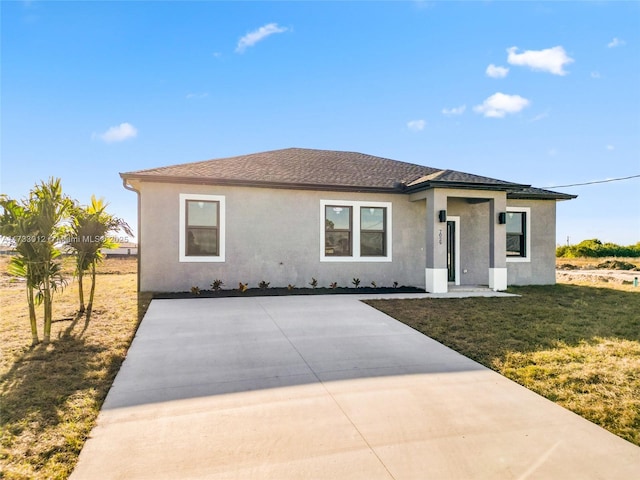 view of front of house with a shingled roof, a front lawn, and stucco siding