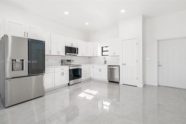 kitchen with stainless steel appliances, light countertops, a sink, and white cabinetry