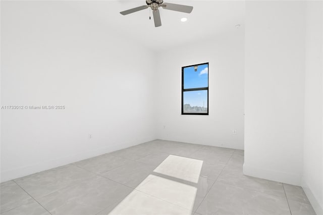 spare room featuring ceiling fan, light tile patterned floors, and baseboards