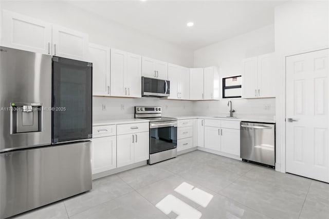 kitchen featuring stainless steel appliances, white cabinets, light countertops, and a sink