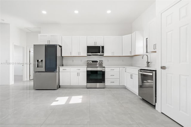 kitchen featuring stainless steel appliances, recessed lighting, light countertops, white cabinetry, and a sink