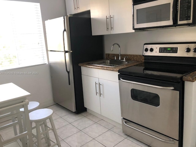 kitchen with sink, light tile patterned flooring, white cabinets, and appliances with stainless steel finishes