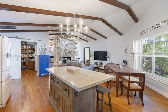 kitchen featuring a fireplace, lofted ceiling with beams, a center island, white fridge with ice dispenser, and light wood-type flooring