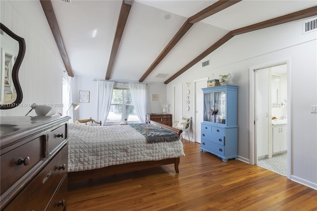 bedroom with connected bathroom, dark hardwood / wood-style flooring, and vaulted ceiling with beams