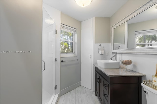 bathroom with a shower with door, vanity, and toilet