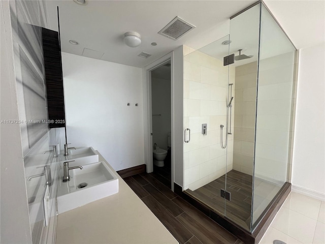 bathroom with vanity, toilet, and a shower with door