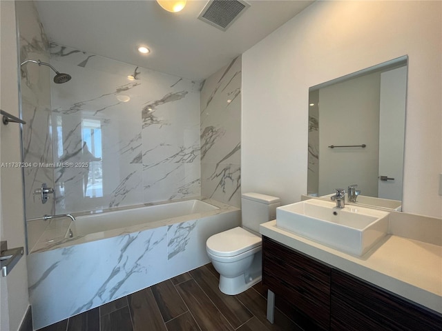 full bathroom with vanity, tiled shower / bath combo, and toilet