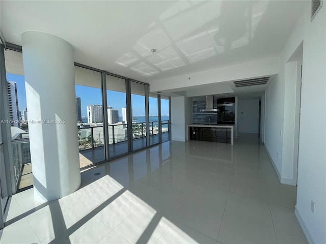 unfurnished room with a wall of windows and light tile patterned floors