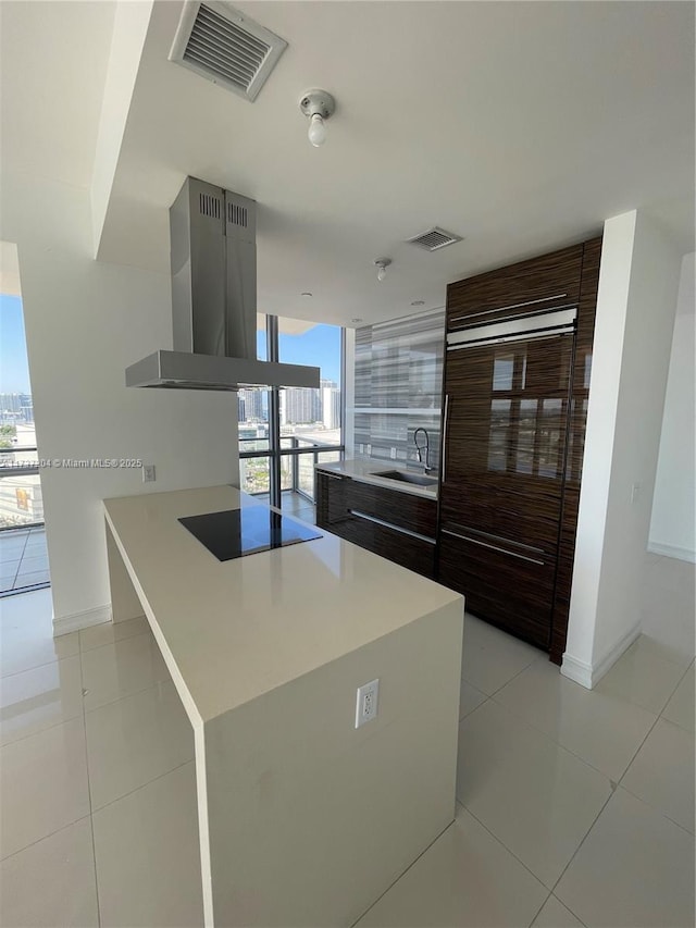 kitchen featuring sink, black electric stovetop, island range hood, expansive windows, and light tile patterned flooring