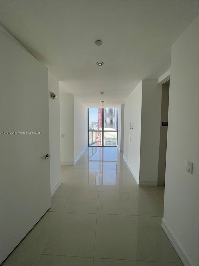 hall with floor to ceiling windows and light tile patterned floors