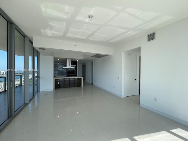 unfurnished living room with light tile patterned flooring and a wall of windows